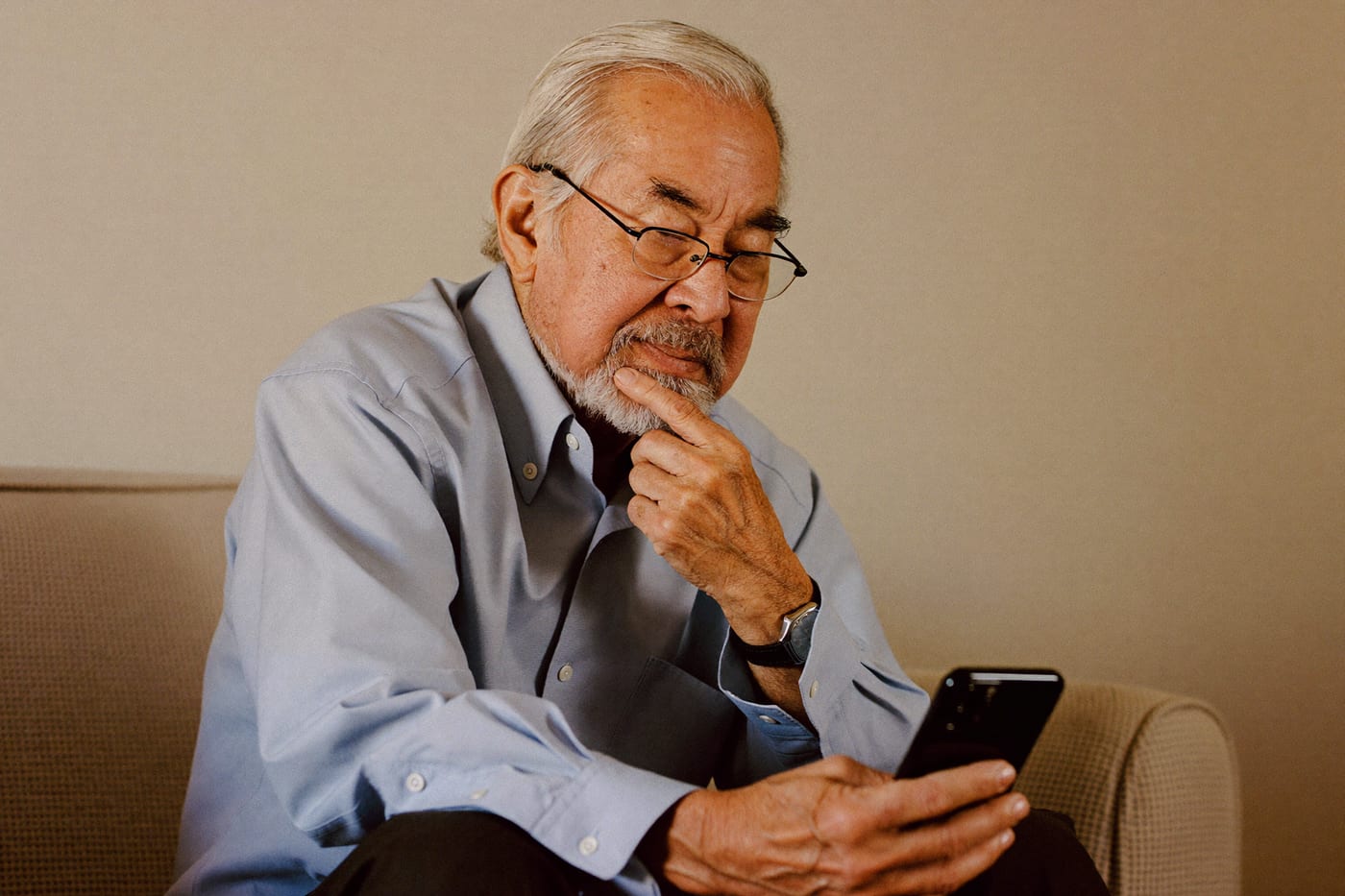 An older man studies a message on his phone, deciding whether to trust it.